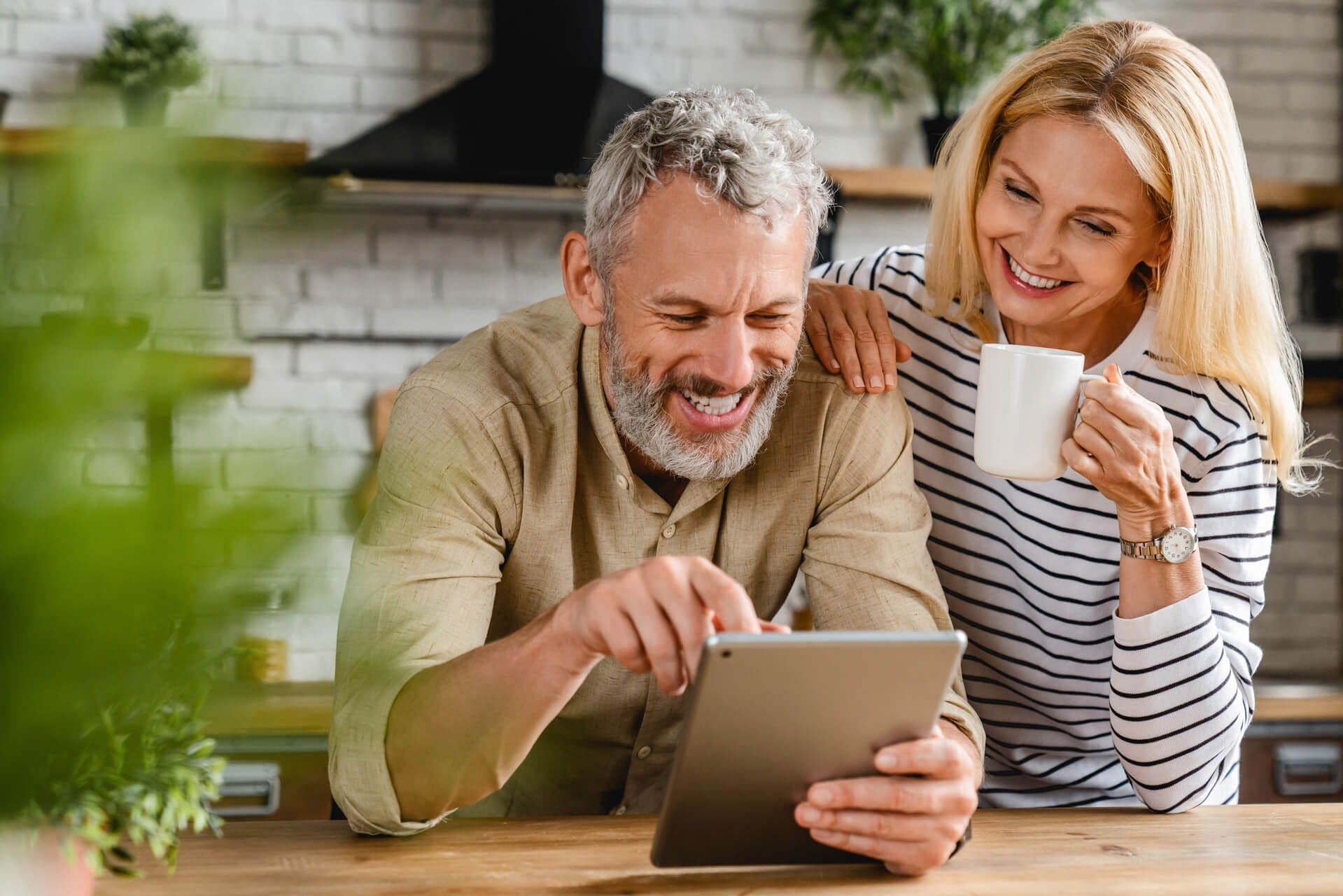 Couple Smiling and drinking coffee while looking at their tablet