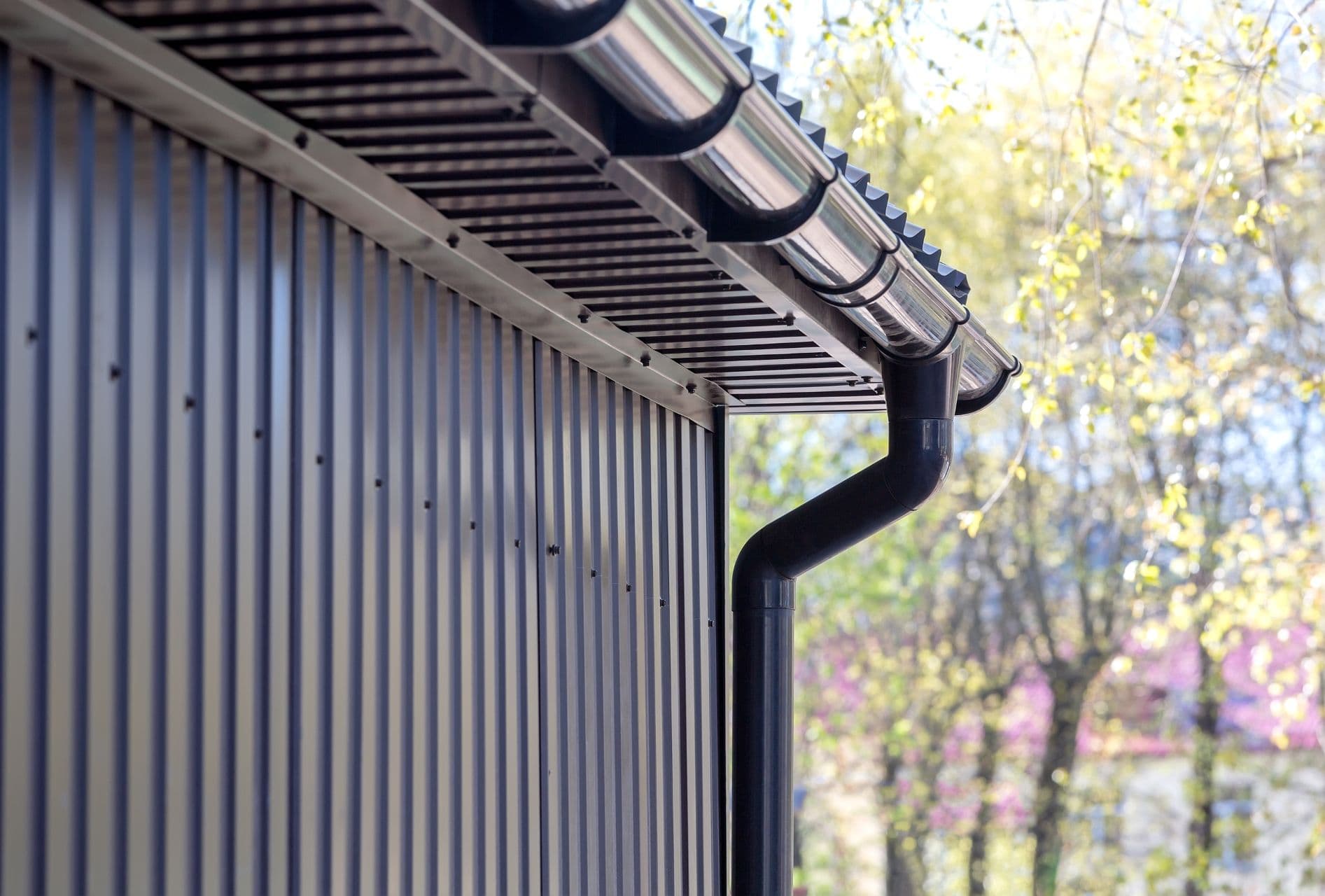 A building with steel siding, gutters, and downspout.