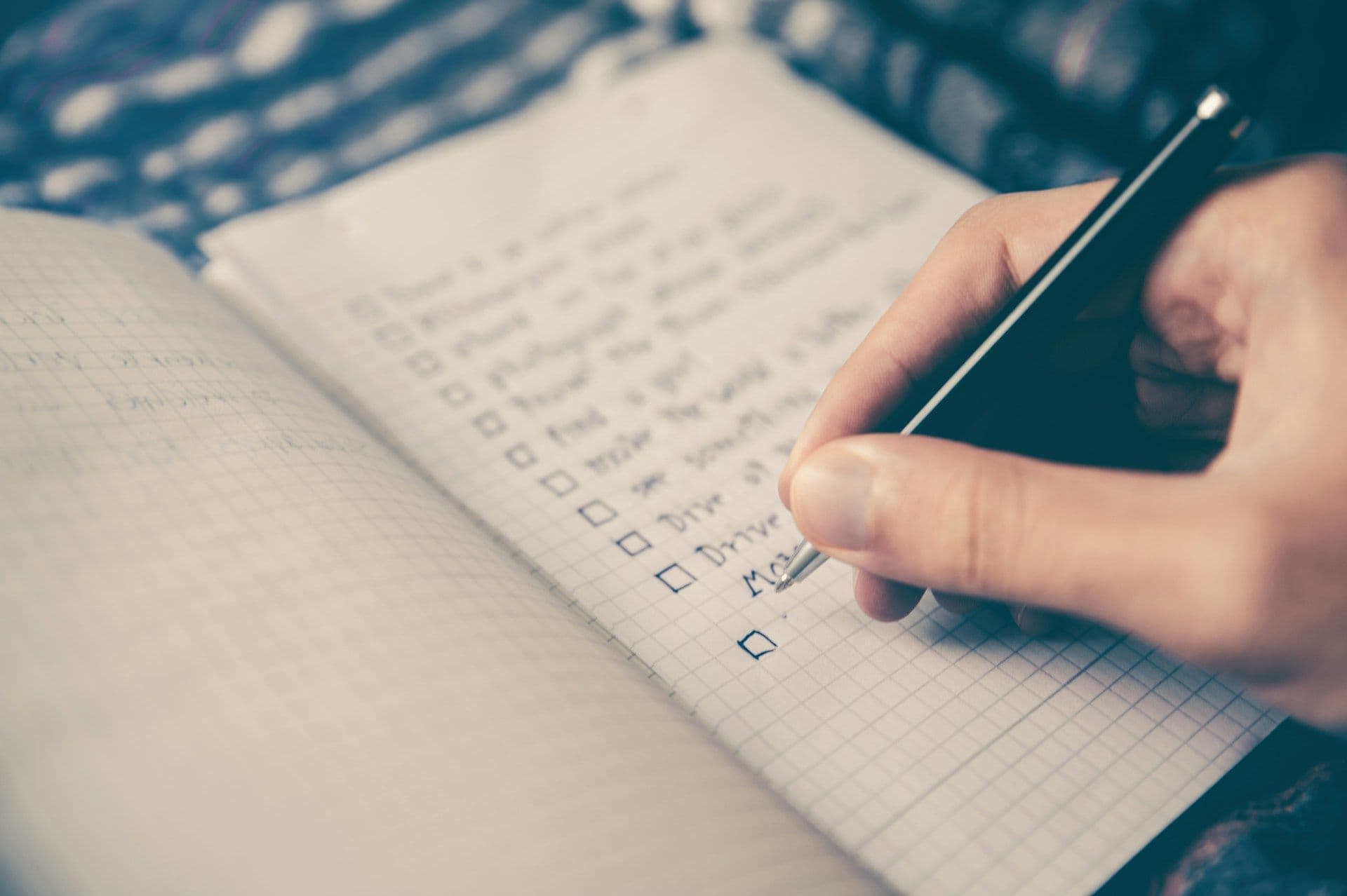 A close up of someone writing a checkbox to do list with how to instructions.