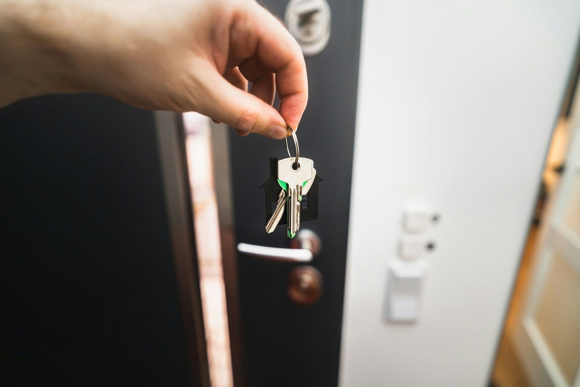 A person holds keys in front of a front door.