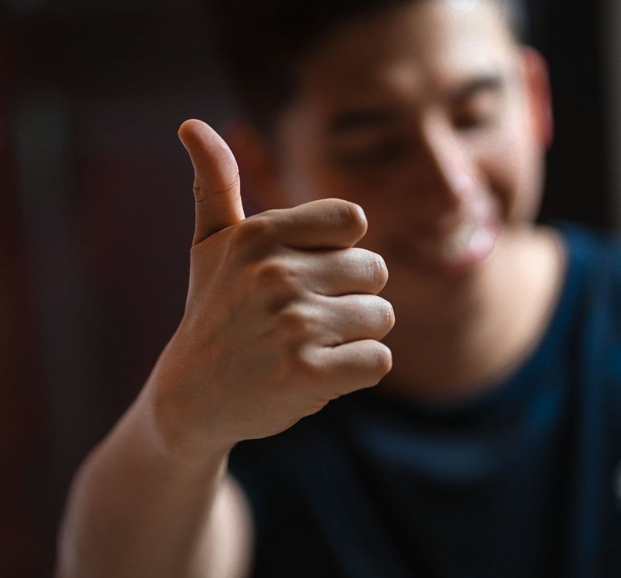 A person holds a thumbs up pose.